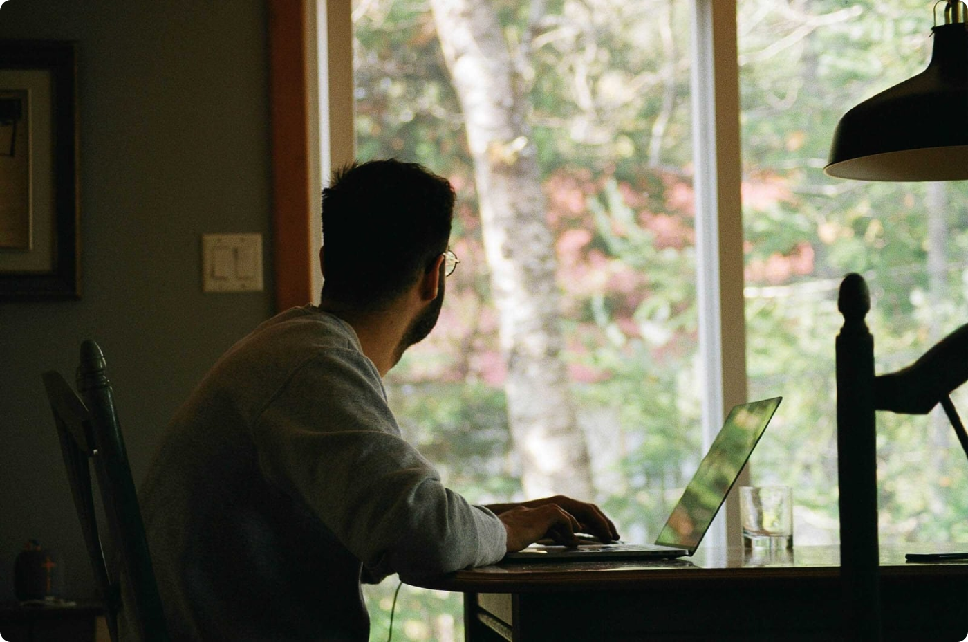 A man looks at the window and works on a laptop